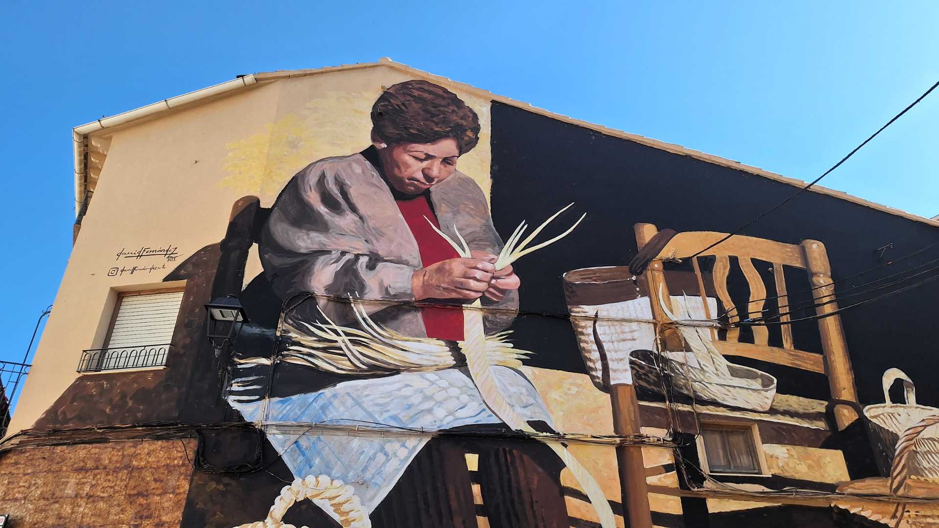 Mural de mujer haciendo capazos de mimbre en Gata de Gorgos